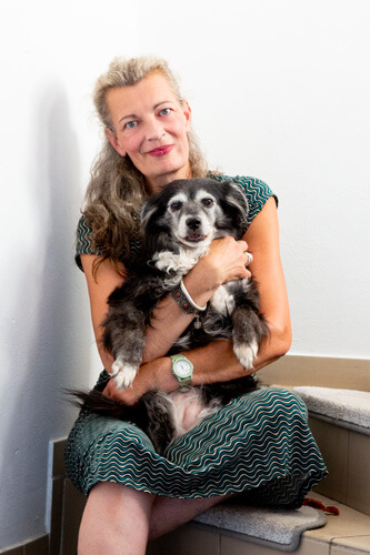 Annely Putz mit ihrem Border Collie "Daphne" im Arm auf der Treppe sitzend.
